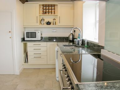 A kitchen with cream cabinets a microwave a wine rack a kettle a sink and a stovetop at The Old Farmhouse Upper Pitts Knighton