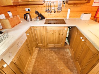 A kitchen with wooden cabinets a kettle a teapot knives hanging utensils and a toaster at Lodge 8 in Louth