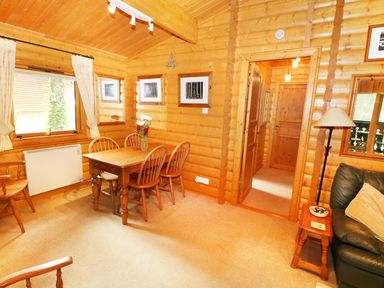 A dining area with a wooden table and four chairs in a wooden cabin interior at Lodge 8 in Louth