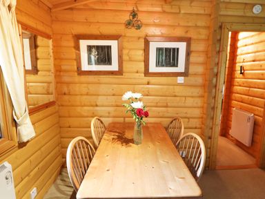 A wooden dining table with four chairs and a vase of flowers in a wooden panelled room at Lodge 8 in Louth