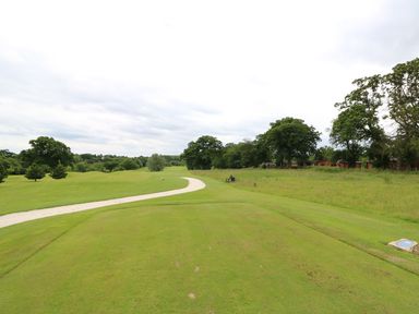 A golf course with a curved gravel path and trees in the background at Lodge 8 in Louth
