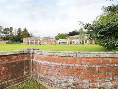 A green lawn with a brick gazebo and brick buildings in the background at Lodge 8 in Louth