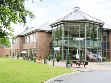 A brick building with large glass windows patio tables and chairs on a lawn at Lodge 8 in Louth