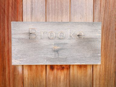 A wooden sign engraved with the word Brooke and a bird mounted on wooden wall panels at Brooke in Exton Rutland