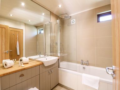 A bathroom with a bathtub and shower a sink on a wooden countertop and a large mirror at Brooke in Exton Rutland