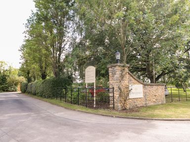 A driveway entrance with stone wall and signs reading barnsdale surrounded by trees and hedges at Brooke in Exton Rutland