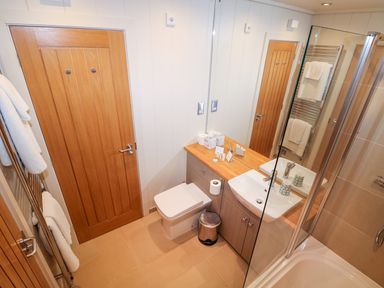 A bathroom with a wooden door a toilet a sink a mirror and a glass shower enclosure at Burley in Exton Rutland