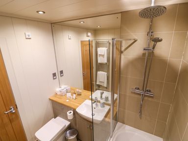 A bathroom with a toilet sink mirror shower and towel rack at Burley in Exton Rutland