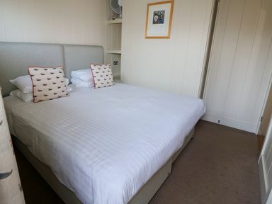 A bedroom with a double bed with white bedding and duck patterned pillows at Burley in Exton Rutland