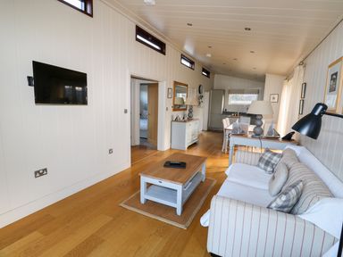 A living room with a striped sofa coffee table wall mounted TV and dining table at Burley in Exton Rutland