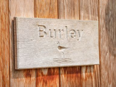 A wooden sign with the word Burley and a bird above water lines mounted on wooden planks at Burley in Exton Rutland