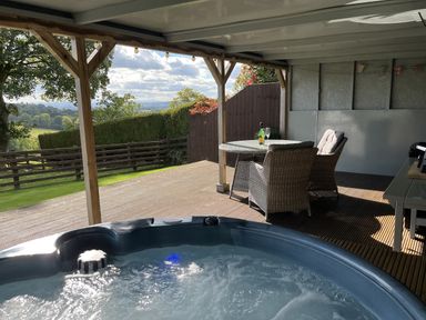 An outdoor area with a hot tub and seating at Shepherds Cabin at Titterstone Clee Hill