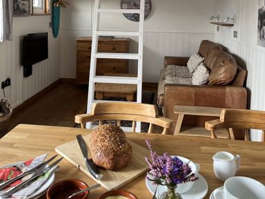 A living room with a dining table and a loaf of bread at Shepherds Cabin at Titterstone Clee Hill