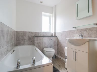 A bathroom with a bathtub toilet and sink cabinet at Bower View in Madley