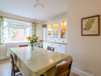 A dining room with a table covered by a polka dot tablecloth and a flower vase by a window at Bower View in Madley