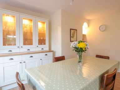 A dining room with a polka dot tablecloth on the table and a vase with flowers at Bower View in Madley