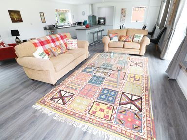 A living room with two beige sofas a glass coffee table and a colorful rug at Heron Lodge in Mavis Enderby near Spilsby