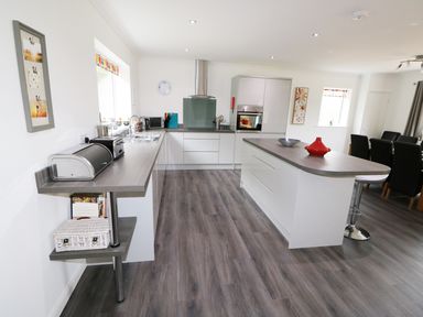 A modern kitchen with an island and dining area at Heron Lodge in Mavis Enderby near Spilsby