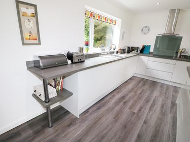 A kitchen with a toaster bread bin microwave and sink under a window at Heron Lodge in Mavis Enderby near Spilsby