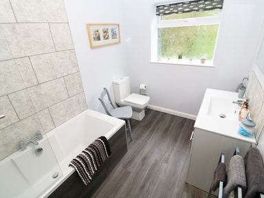 A bathroom with a bathtub a toilet a sink a chair and a window at Heron Lodge in Mavis Enderby near Spilsby
