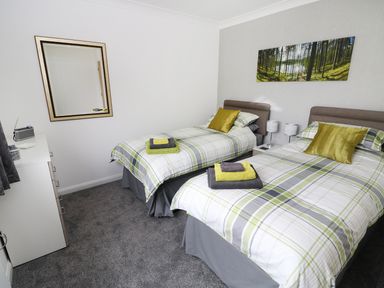 A bedroom with two single beds with plaid bedding and towels on each bed at Heron Lodge in Mavis Enderby near Spilsby
