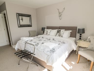 A bedroom with a bed with pillows and folded towels bedside tables lamps and chairs at Manor House in Warkworth