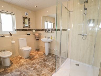 A bathroom with a shower enclosure toilet bidet pedestal sink and a window at Manor House in Warkworth