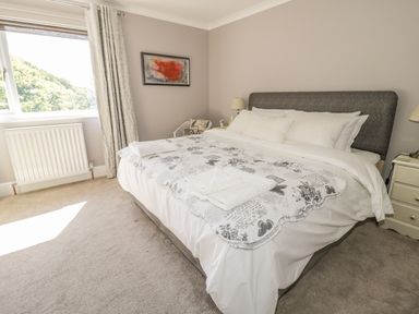A bedroom with a large bed white bedding bedside tables lamps a window and a framed picture at Manor House in Warkworth