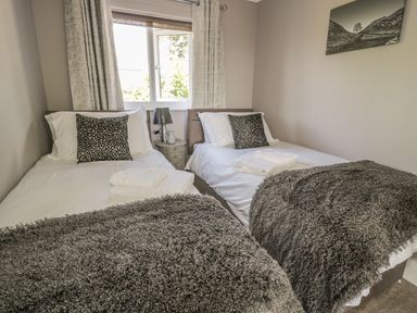 A bedroom with two single beds with white linens and dark gray throws at Manor House in Warkworth