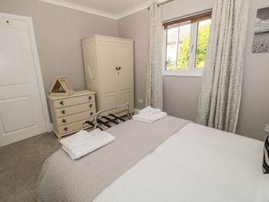 A bedroom with a bed towels on a luggage rack a chest of drawers and a wardrobe at Manor House in Warkworth