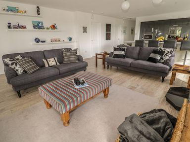 A living room with two gray sofas a striped ottoman and shelves with decorative items at Manor House in Warkworth