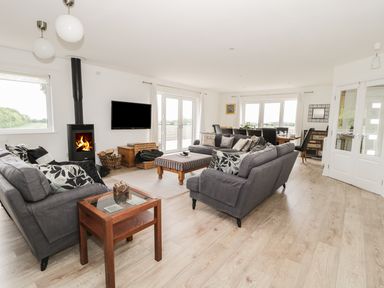 A living room with two gray sofas a glass side table a wood burning stove and a dining table at Manor House in Warkworth