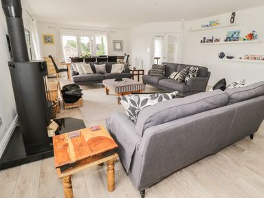 A living room with gray sofas wooden tables and a dining area at Manor House in Warkworth