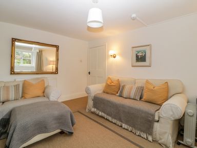 A living room with two sofas with cushions and throws a large mirror on the wall a wall lamp and a framed picture at Crannacombe Farmhouse in Loddiswell