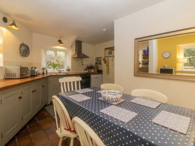 A kitchen with a dining table covered in a polka dot tablecloth and chairs at Crannacombe Farmhouse in Loddiswell