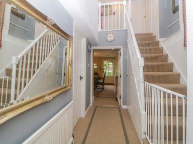 A hallway with stairs on both sides a large mirror on the wall and a dining room visible through a doorway at Crannacombe Farmhouse in Loddiswell