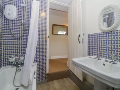 A bathroom with a bathtub shower combination and sink with a mirror at Crannacombe Farmhouse in Loddiswell