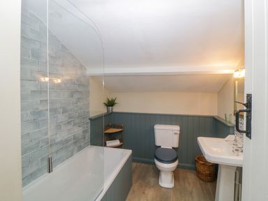 A bathroom with a bathtub tile wall toilet sink and a basket at Crannacombe Farmhouse in Loddiswell