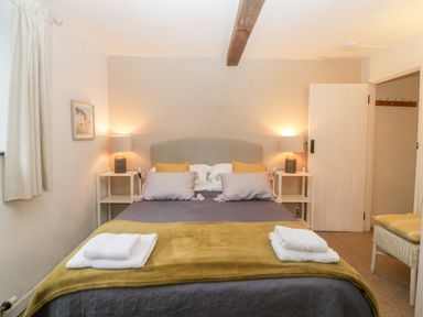 A bedroom with a double bed two bedside tables with lamps and folded towels on the bed at The Cider Barn in Loddiswell