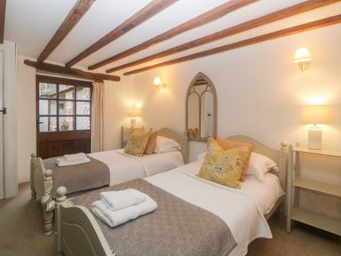 A bedroom with two single beds wooden ceiling beams and a wooden door at The Cider Barn in Loddiswell