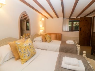 A bedroom with two single beds a wooden crib a window and wooden beams on the ceiling at The Cider Barn Loddiswell