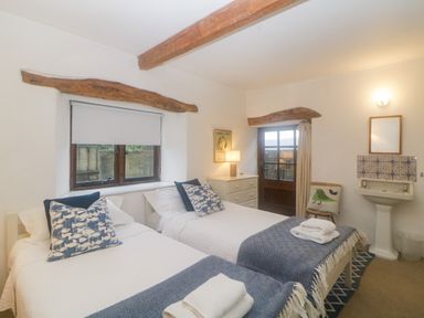 A bedroom with two single beds pillows dresser and a washbasin at The Cider Barn in Loddiswell