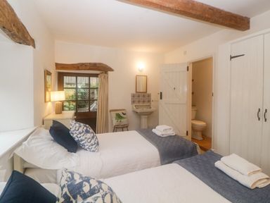 A bedroom with two single beds and a sink with a mirror at The Cider Barn in Loddiswell