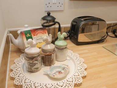 A kitchen counter with a teapot shortbread biscuits three jars with rooster lids a French press and a toaster at Robins Nest Whitby