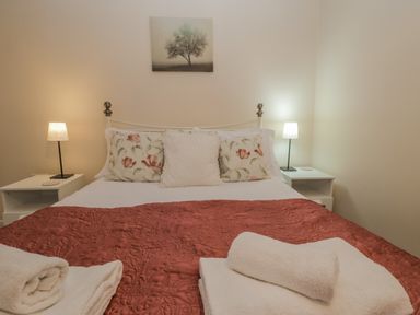 A bedroom with a bed covered by a red quilt and white towels at Robins Nest in Whitby