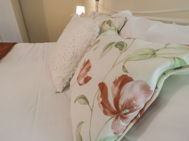 A bed with white sheets and decorative pillows including one with a floral pattern at Robins Nest in Whitby