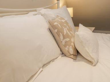 A bed with white pillows and a beige pillow with butterfly patterns at Robins Nest in Whitby