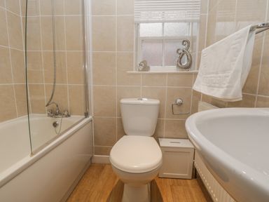 A bathroom with a bathtub shower toilet sink towel rail and window at Robins Nest in Whitby