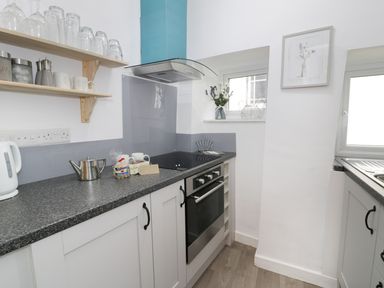 A kitchen with a stove oven countertop shelves and two windows at Ty Coed in Llanberis