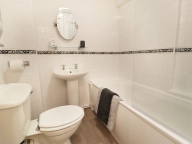 A bathroom with a toilet sink and bathtub with towels at Ty Coed in Llanberis